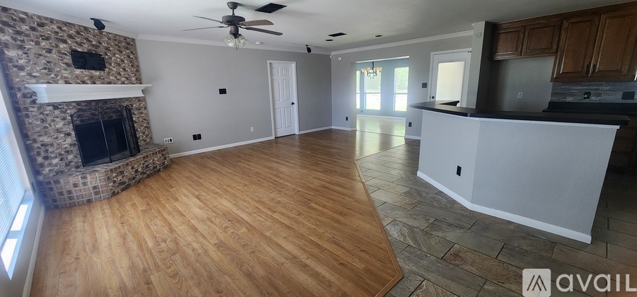 A spacious living room with a stone fireplace and hardwood floors.