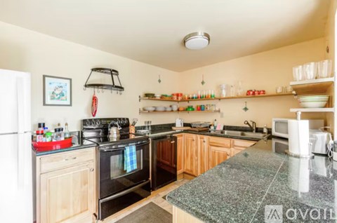 A kitchen with a black stove top oven and wooden cabinets.