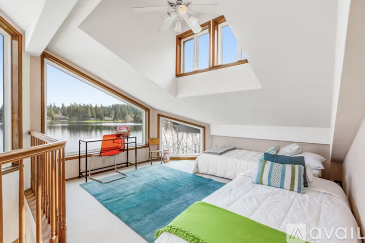 A bedroom with a large bed and a view of a lake through the window.