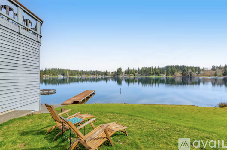 Two chairs are on the lawn by the lake.