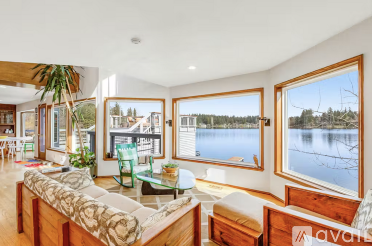 A living room with a couch, a table, and a view of a lake through the windows.