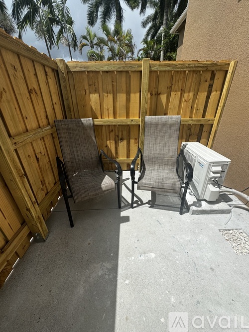 Two chairs are placed in front of a wooden fence.