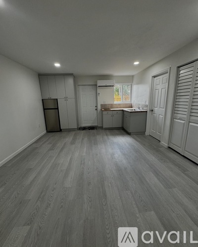 A spacious room with wooden flooring and white walls.
