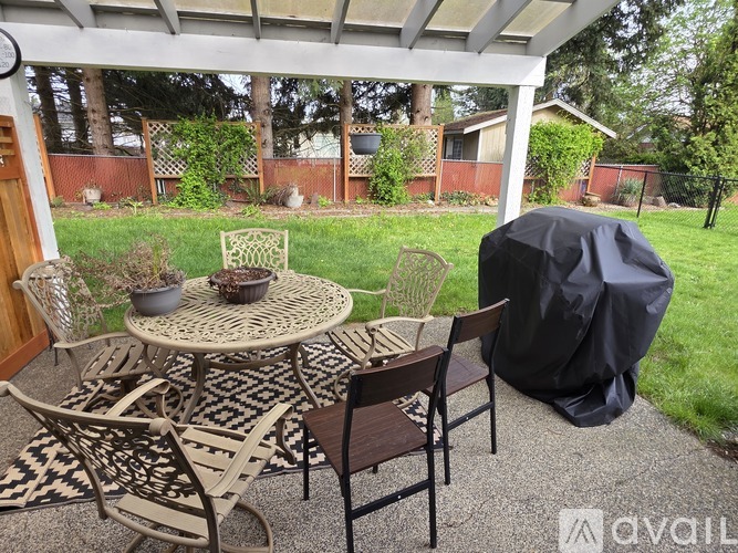 A patio with a round table and chairs under a roof.