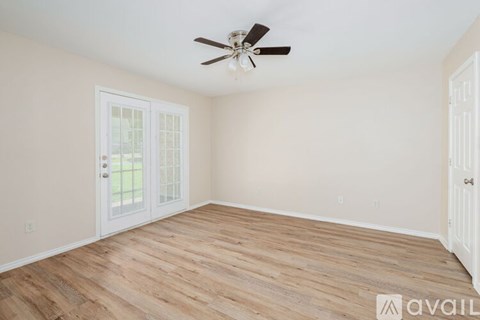 A room with a ceiling fan and wooden flooring.