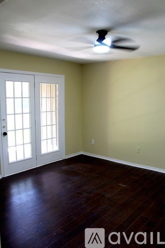 A spacious room with a ceiling fan and wooden flooring.