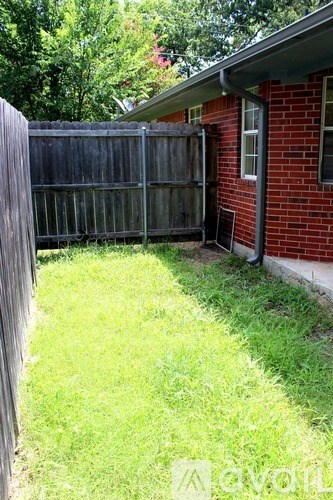 A red brick house with a wooden fence and green grass.