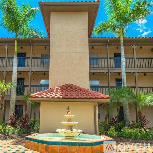 A fountain in front of a building with a balcony.
