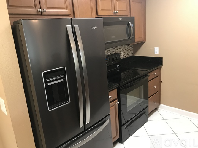 A black fridge and microwave in a kitchen.