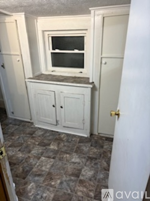A small white cabinet with a window sits in a room.