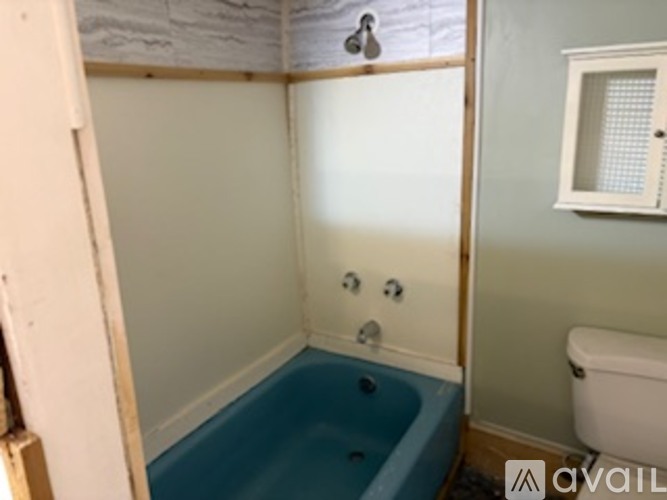 A bathroom with a blue tub and a white toilet.