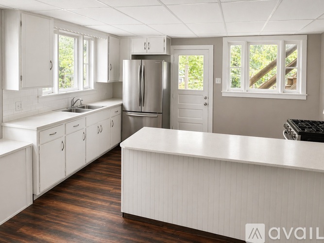 A kitchen with white cabinets and a stainless steel refrigerator.