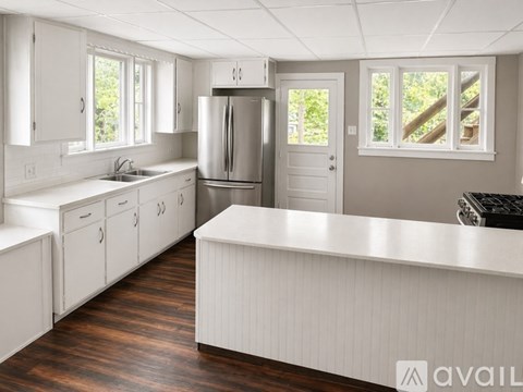 A kitchen with white cabinets and a stainless steel refrigerator.