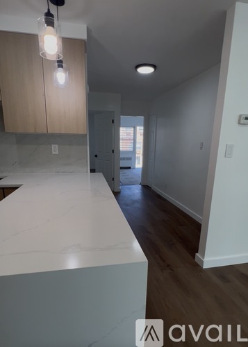 A kitchen with a marble counter top and wooden cabinets.