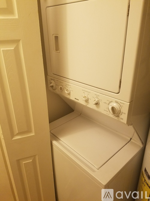 A white dryer is in a small space next to a door.