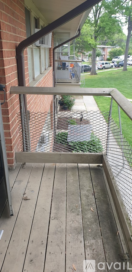 A wooden deck with a metal railing and a brick wall.