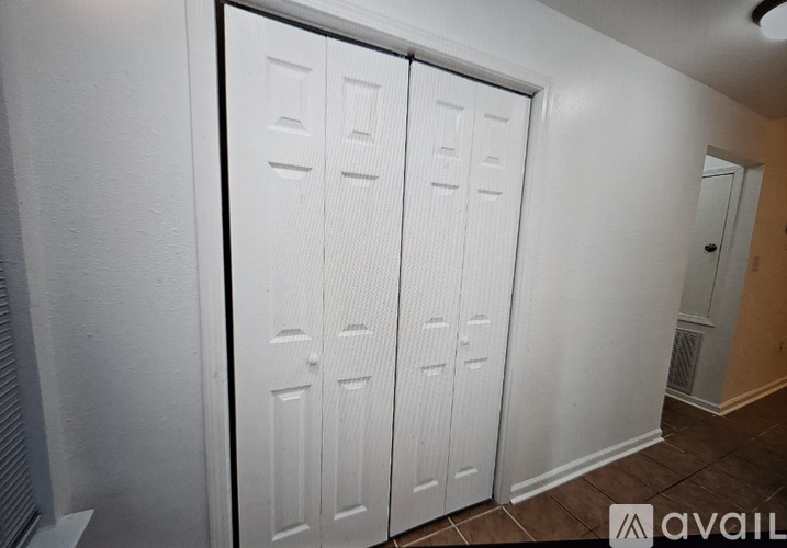 Closet with white doors and a brown floor.