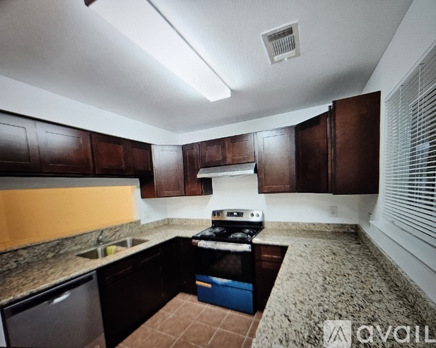 A kitchen with brown cabinets and a granite countertop.
