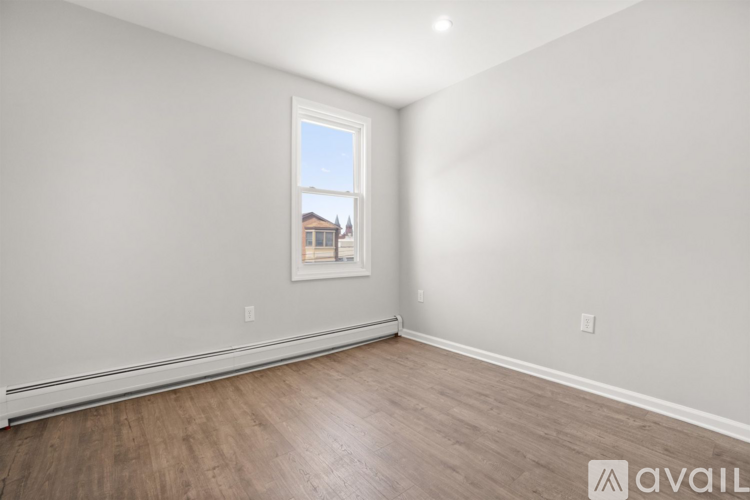 A room with wooden flooring and a window showing a building outside.