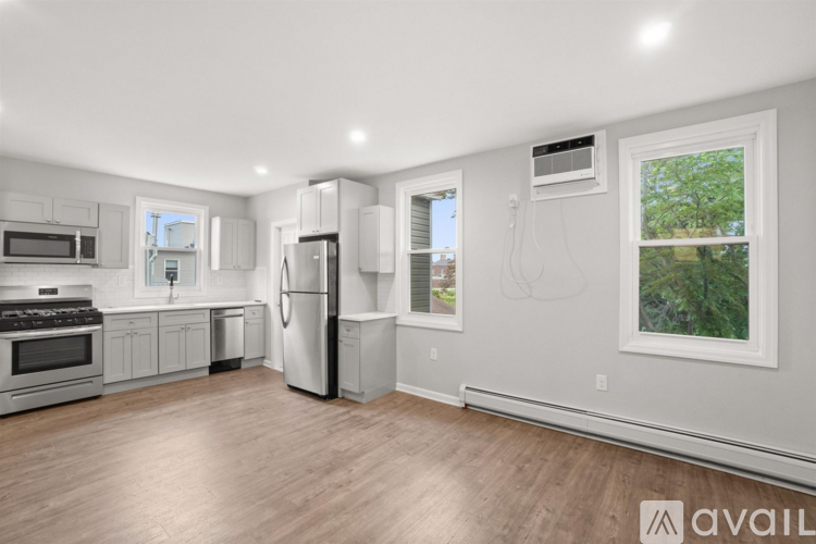 A spacious kitchen with white appliances and wooden flooring.