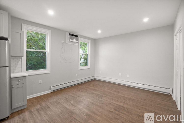 A spacious room with wooden flooring and a window.