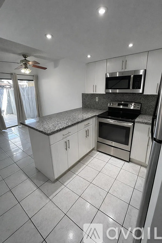 A kitchen with white cabinets and a granite countertop.