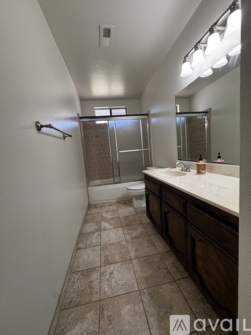 A bathroom with a tiled floor and a large mirror.