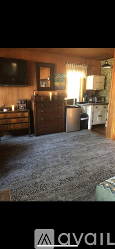 A living room with a television, a dresser, and a window with curtains.