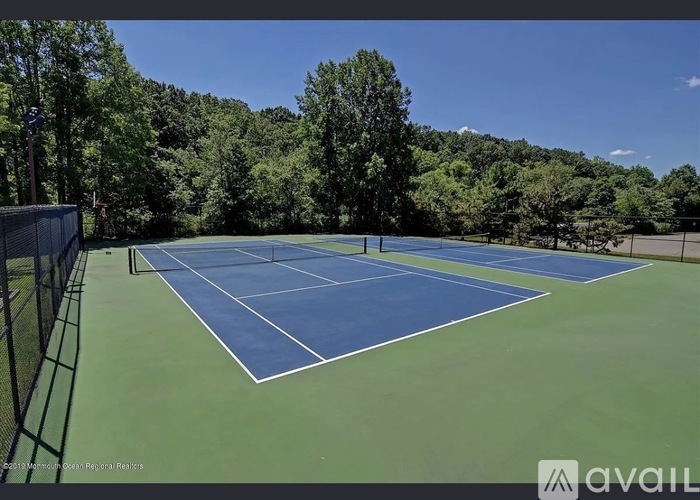 A tennis court surrounded by trees and a fence.