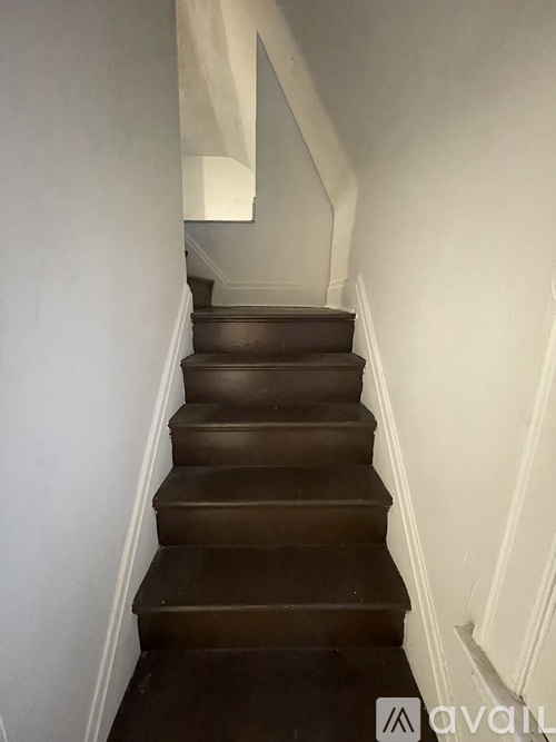 A staircase with a white wall on the left and a white baseboard on the right.