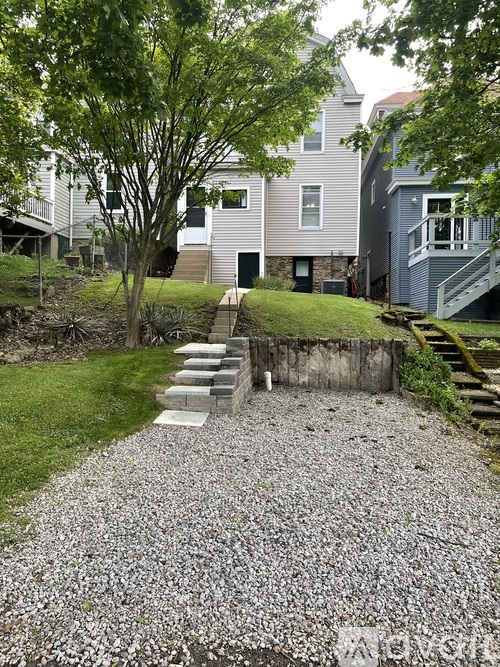 A gravel path leads to a house with a grey and white exterior.