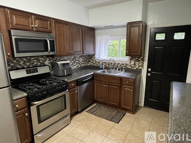 A kitchen with brown cabinets and a black door.
