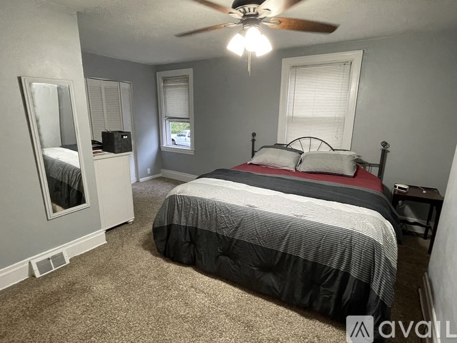 A bedroom with a bed, dresser, and window.