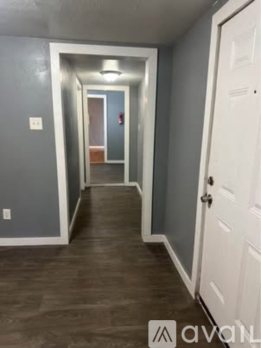 A hallway with a white door on the right and a mirror on the wall.