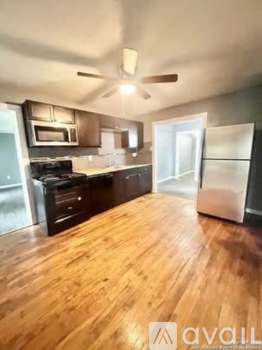 A kitchen with wooden floors and a refrigerator on the right.