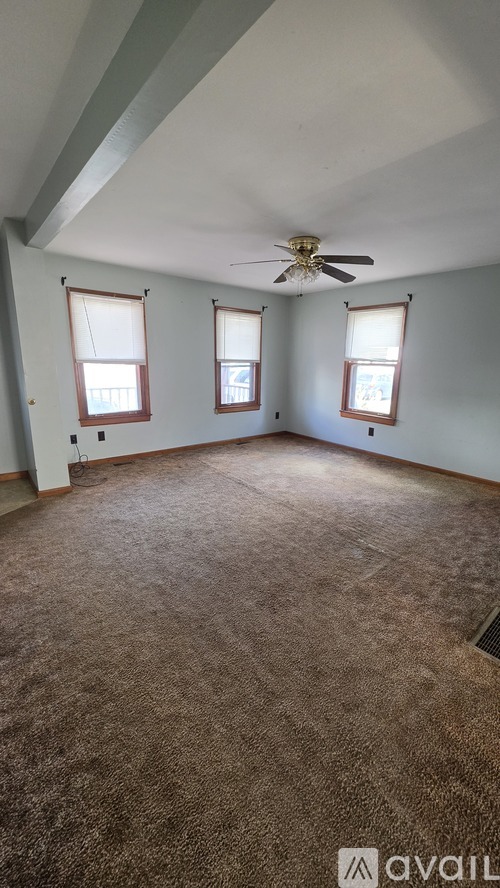 A room with a ceiling fan and carpeted floor.