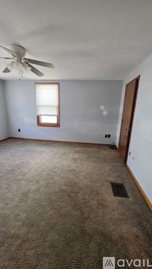 A room with a ceiling fan and carpeted floor.