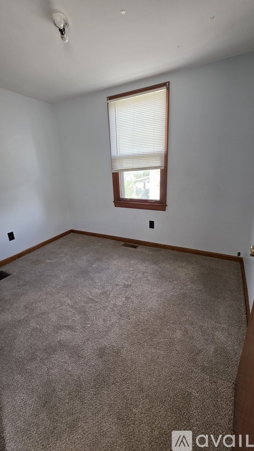 A room with a carpeted floor and a window with blinds.