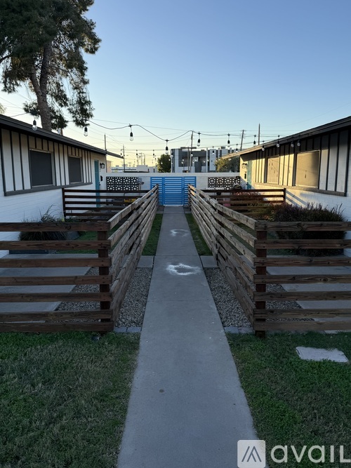 A pathway leads to a blue gate between two wooden fences.