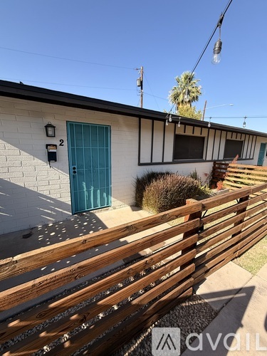 A wooden fence in front of a house with a blue door.