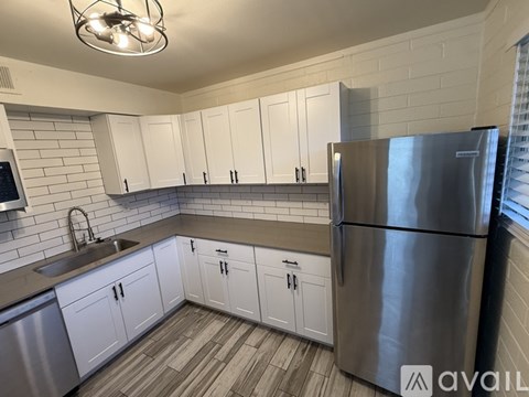 A kitchen with white cabinets and a stainless steel refrigerator.