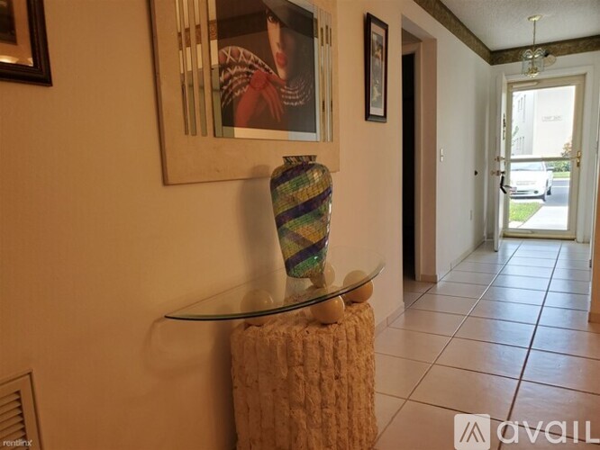 A glass table with a vase on it and a picture on the wall.