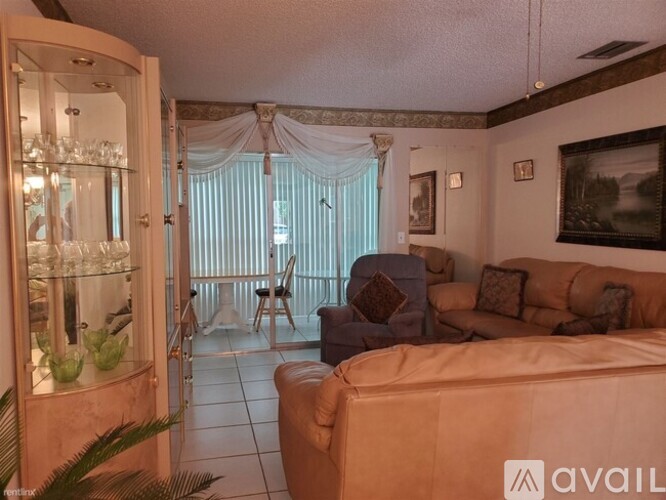 A living room with a sofa, a chair, a table, a plant, and a painting on the wall.