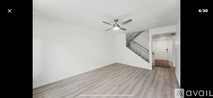 A room with a ceiling fan and wooden flooring.