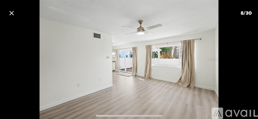 A spacious room with a ceiling fan and large windows.