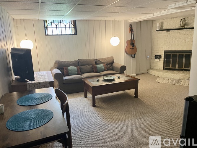 A living room with a fireplace and a guitar hanging on the wall.