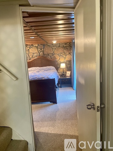 A bedroom with a bed and a stone wall.