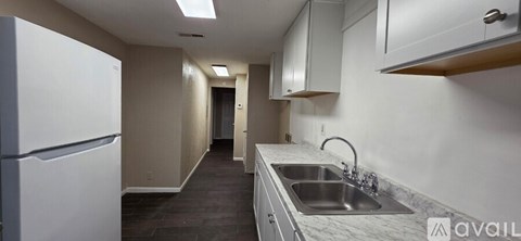 A kitchen with a white fridge and a sink.