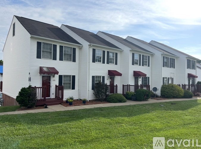 A row of white houses with red awnings and green bushes in front.