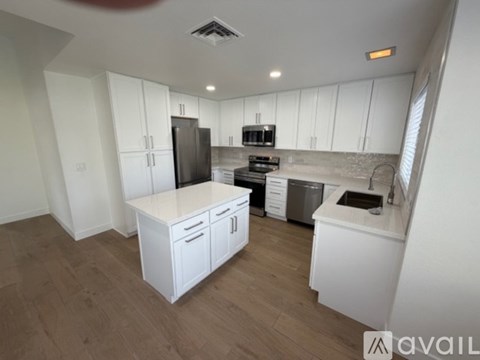 A kitchen with white cabinets and a wooden floor.
